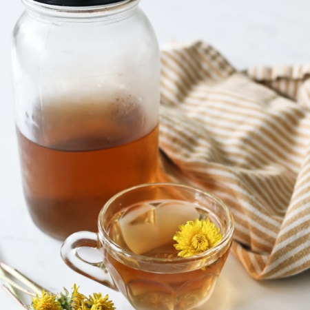 A cup of roasted dandelion root tea and a jar of the same tea