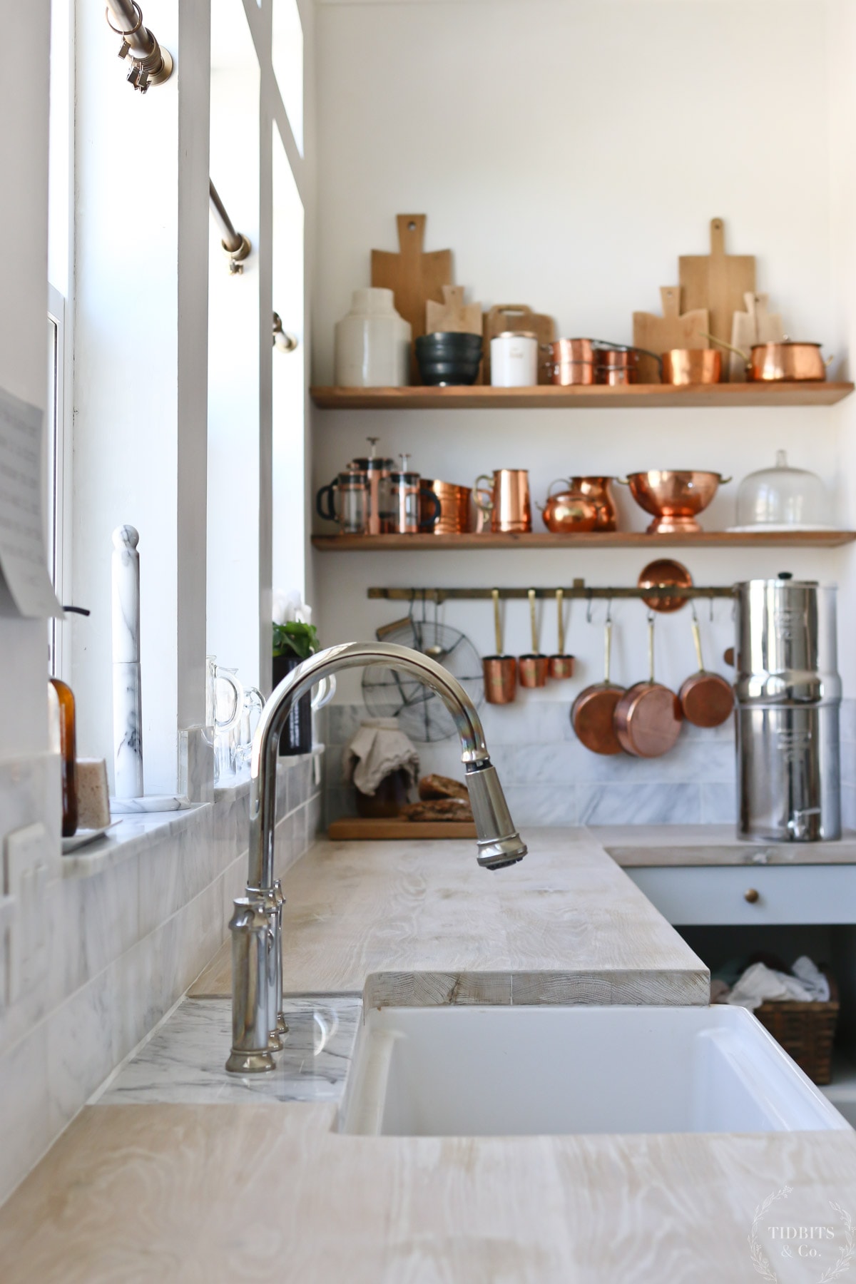 A shot of a kitchen sink, butcher block countertops and open shelving in a farmhouse kitchen