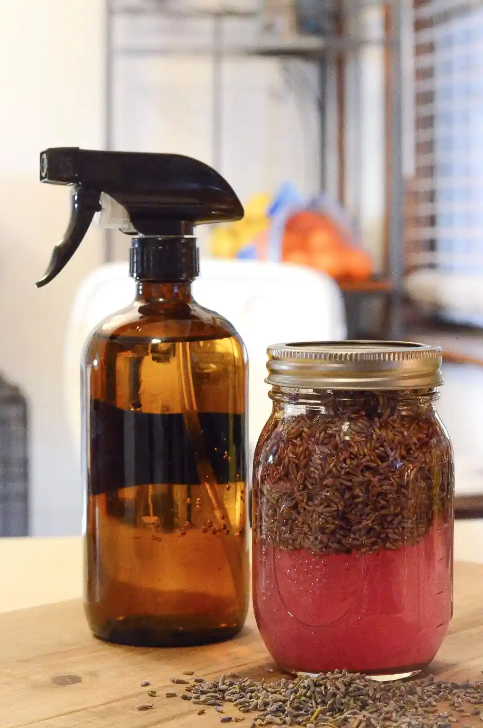 A brown spray bottle and a mason jar full of lavender infused vinegar sit on a counter