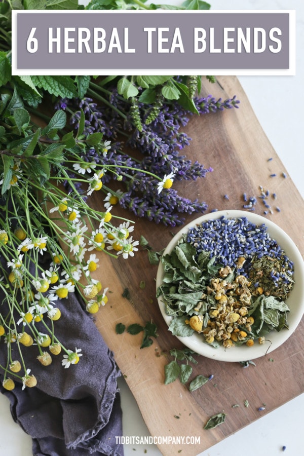 Several types of herbs sit on a table and in a white bowl