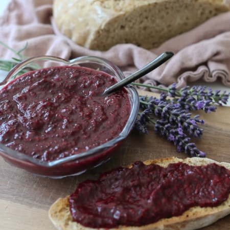 Lavender berry jam on a slice of bread and in a glass bowl