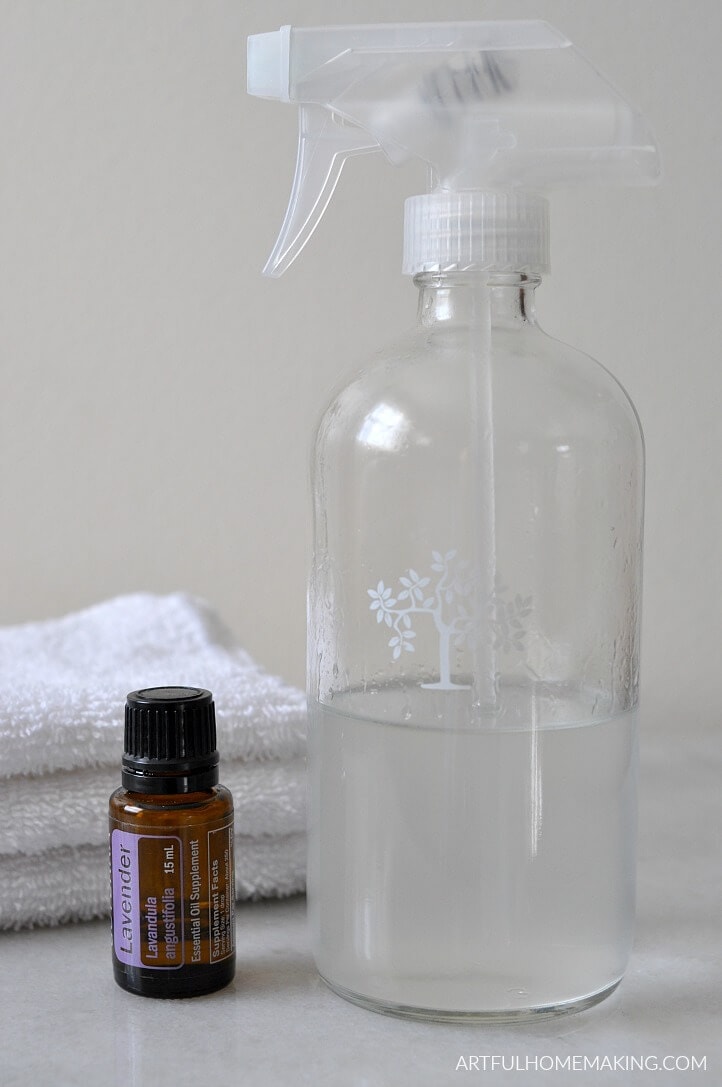 A clear spray bottle and lavender essential oil wait to be made into lavender linen spray