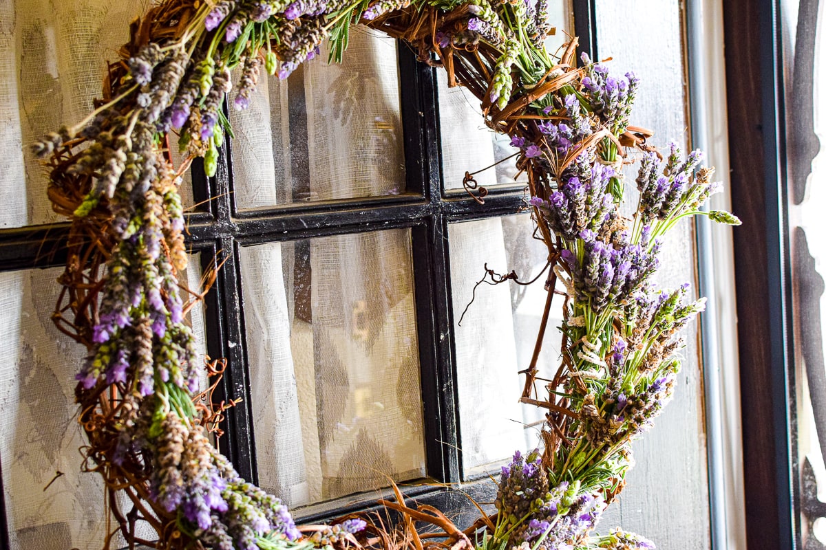 A lavender grapevine wreath hands on a door