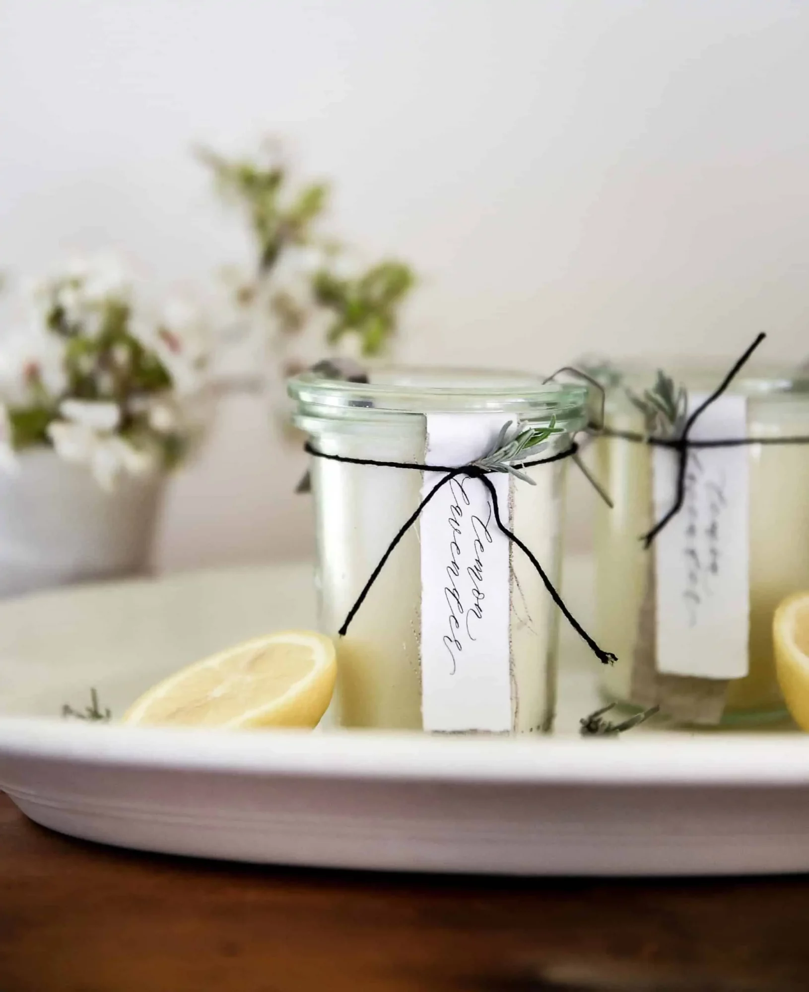 Glass jars hold two lemon lavender candles on a white plate