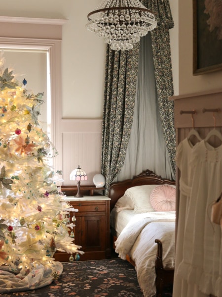 A cottage core bedroom decorated with a white Christmas tree