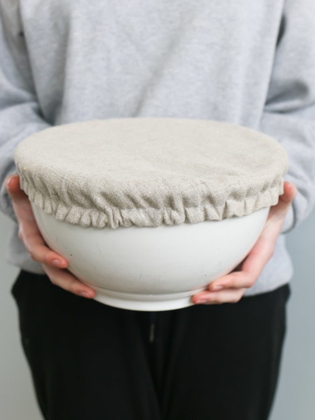 A girls holds a large bowl with a homemade linen bowl cover
