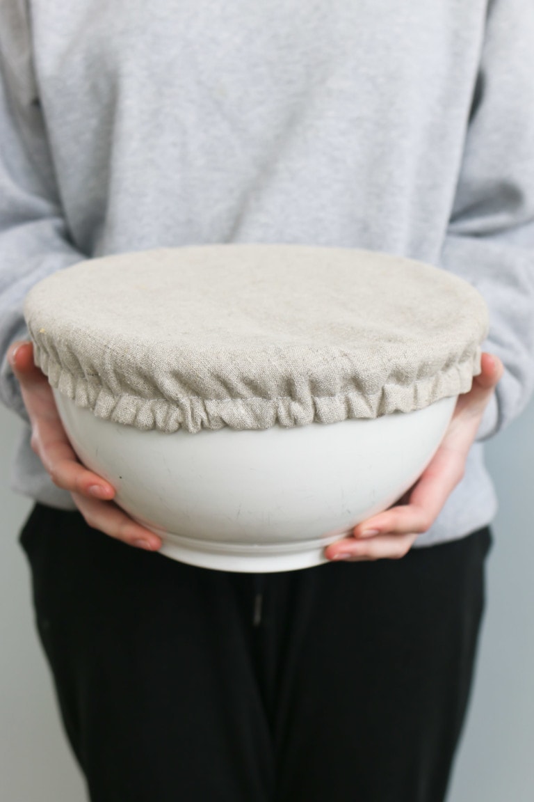 A girls holds a large bowl with a homemade linen bowl cover