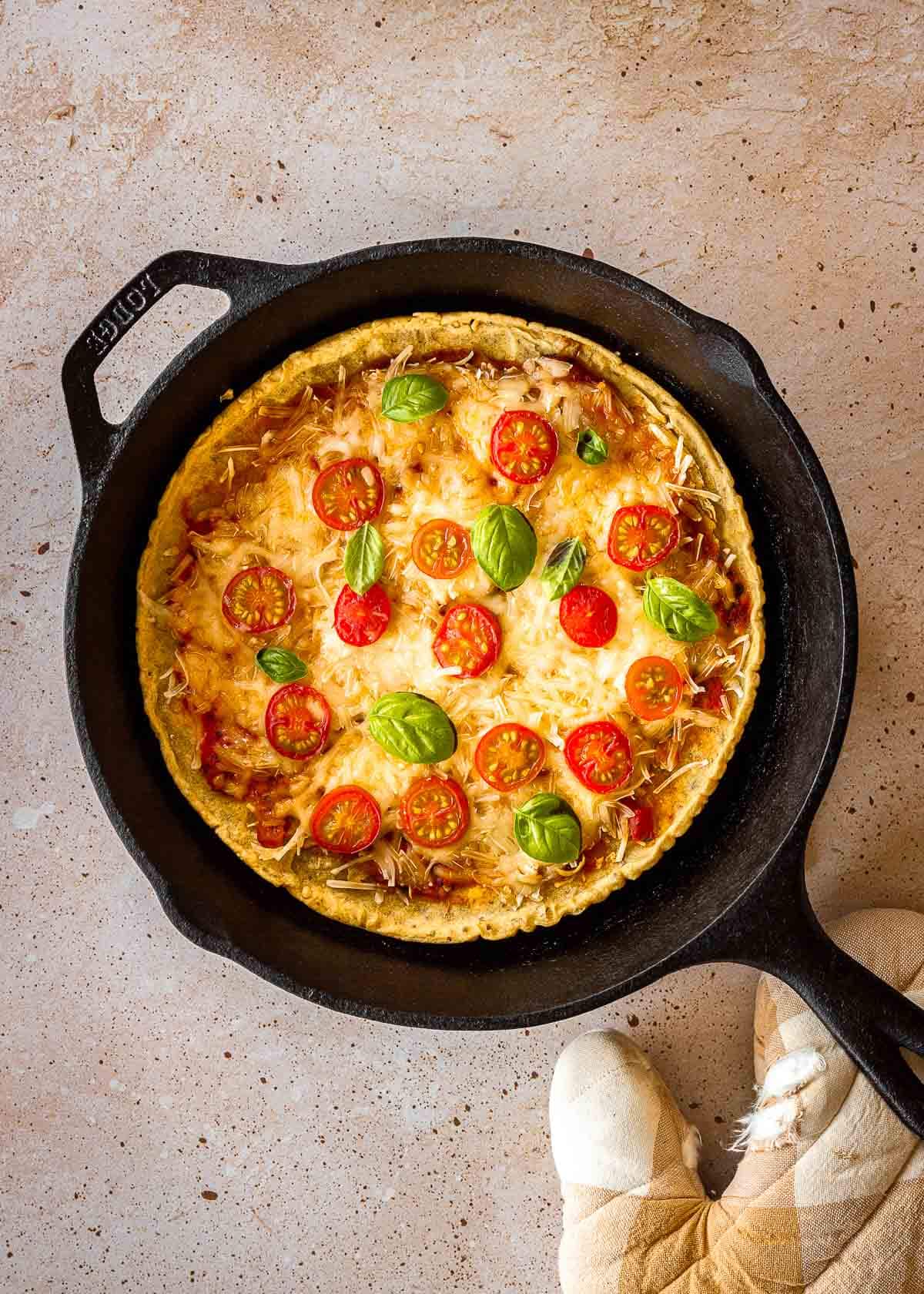 A pizza with chickpea flour pizza crust in a cast iron pan