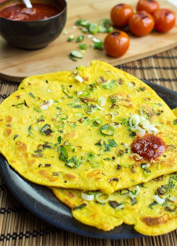 A stack of savory chickpea flour pancakes with green onions