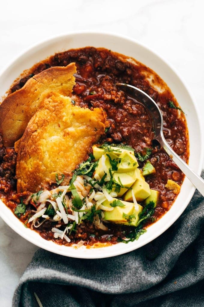 Socca made from a garbanzo bean flour recipe sits in a bowl of soup with avocado and cheese toppings
