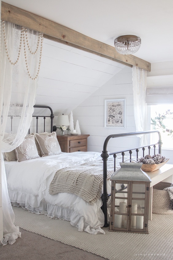 A white bed with layers of white bedding in a barndominium bedroom