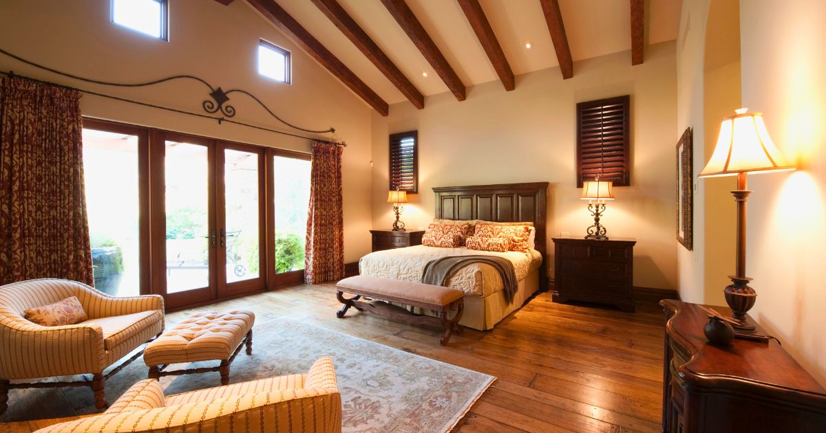 A large pole barn home bedroom with a bed, chairs and a vaulted ceiling