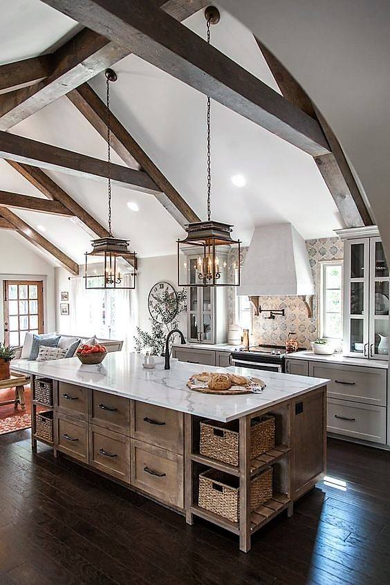 A beautiful farmhouse barndominium kitchen with island, wood beams and vintage light fixtures