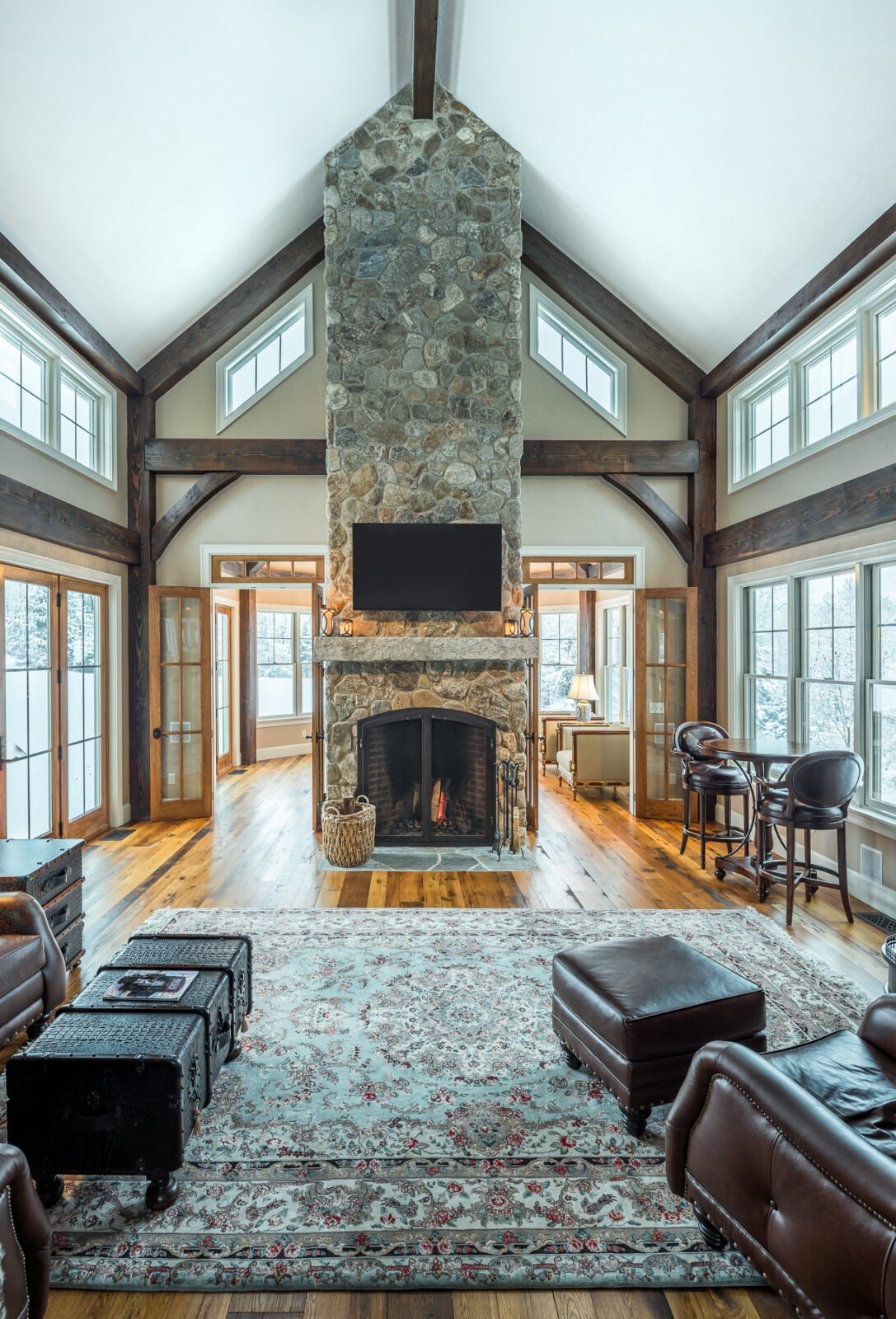 A pole barn home living room with a two story fireplace and large windows