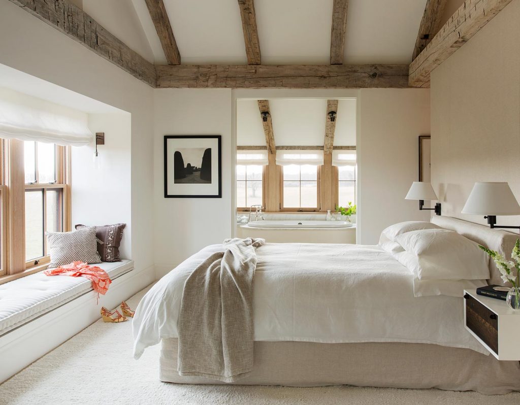 A  bed sits in a barndominium bedroom with a blend of rustic and modern design elements