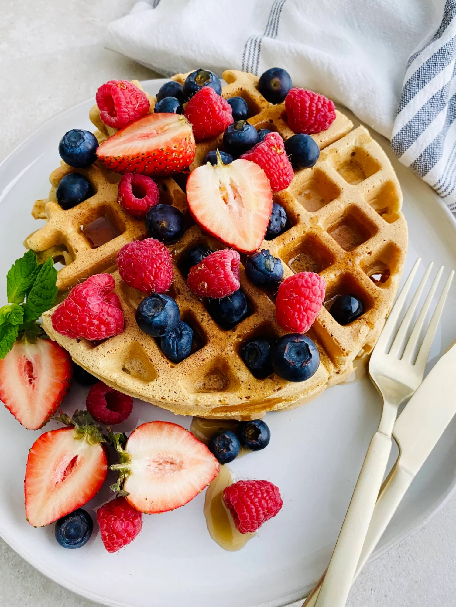 Waffles are topped with pieces of assorted fruit