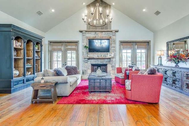 A beautiful barndominium interior living room with a red rug and red arm chairs