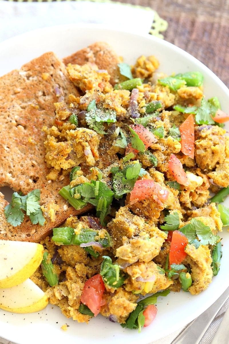 A chickpea scramble made from chickpea flour and vegetables is served on a plate with toast