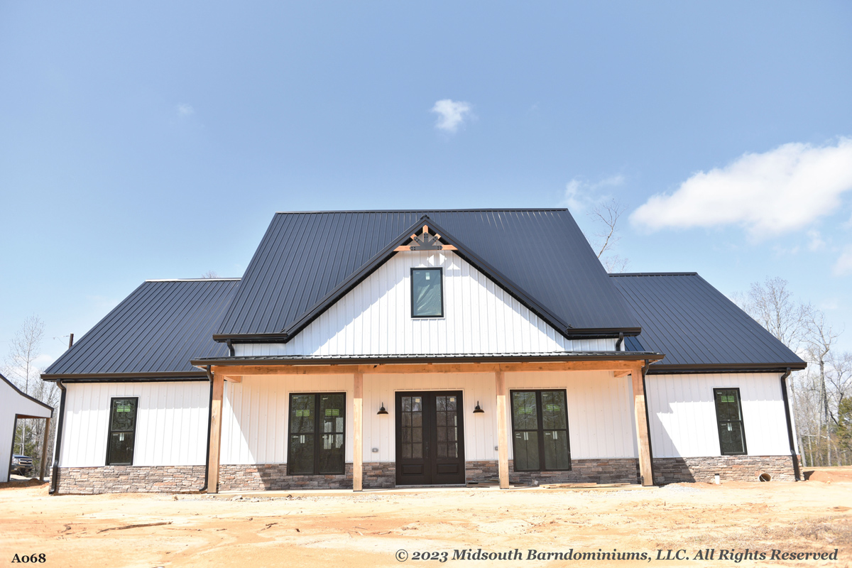 A barndominium house exterior with black metal roof and white siding